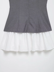 Detailed view of the layered white ruffle hem on a grey pleated poplin mini dress