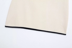 Detail shot of beige knit fabric with fine ribbed texture and black contrast hem trimming