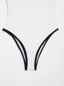 Detail view of white bodysuit with black piping and high-cut leg opening stitching