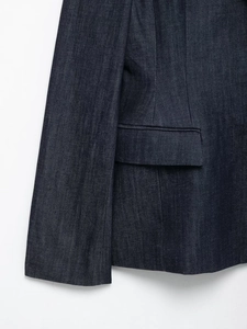 Vue détaillée du blazer en denim bleu foncé montrant la texture du tissu et le rabat de poche