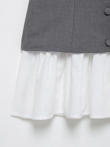 Detail of dark grey tailored fabric with buttons and white pleated skirt hem