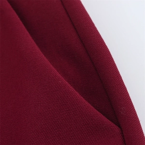 Gros plan du tissu bordeaux texturé montrant les coutures détaillées de la poche latérale