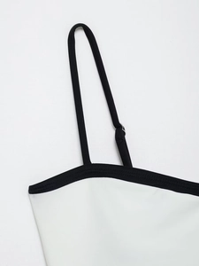 Close-up of adjustable black shoulder strap with silver buckle on white bodysuit