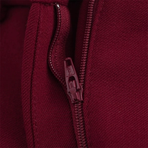 Détail d'un pantalon de costume bordeaux avec fermeture éclair YKK de haute qualité assortie