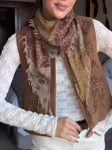 Close-up of vintage embroidered vest with fringe edges and bohemian style patterns