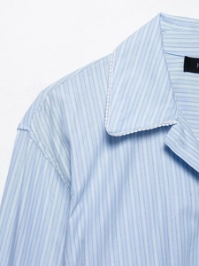 Gros plan sur la chemise à rayures bleu clair avec garniture en dentelle blanche sur le col
