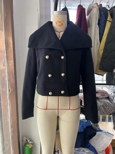 Close-up of black wool blend double-breasted jacket with golden buttons and lapel collar