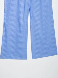 Detalle de pantalones anchos de cuadros vichy azules y blancos con encaje blanco ondulado