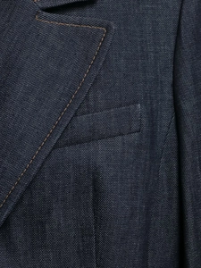 Détails d'un blazer en denim bleu foncé avec surpiqûres contrastées et col à revers