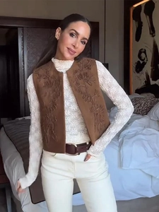 Close-up of floral embroidery on brown suede vest with bohemian vintage style texture