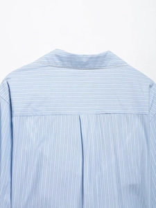 Détail de la chemise rayée bleu clair montrant le col en dentelle blanche et le pli arrière