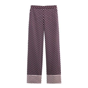 Detail of high-waisted wide-leg trousers featuring a navy geometric diamond pattern and wide cuffs