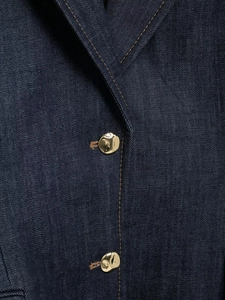 Gros plan d'un blazer en jean bleu foncé avec boutons dorés et coutures contrastées