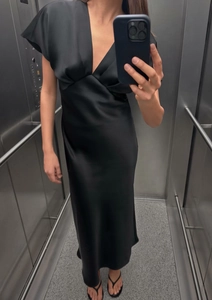 Détail d'une robe longue élégante en soie noire avec col en V et manches courtes en miroir