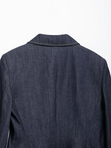 Vue détaillée d'un blazer en jean indigo avec revers crantés et surpiqûres orange contrastées
