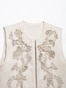 Detail of vintage beige suede vest with intricate 3D floral embroidery and smooth texture