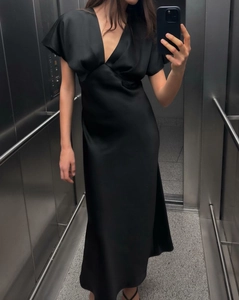 Détail d'une robe longue en satin noir avec décolleté en V et manches à volants