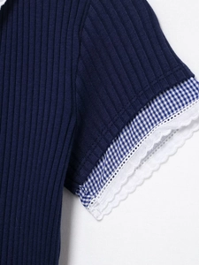 Dettaglio manica in maglia a coste blu navy con bordo a quadretti e pizzo bianco