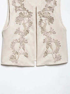 Close-up of 3D floral embroidery on beige sleeveless vest with suede texture