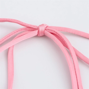Détail macro de fines bretelles en satin rose et texture soyeuse sur la robe longue