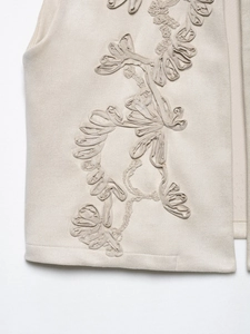 Detail of vintage beige vest featuring 3D floral embroidery on soft suede fabric