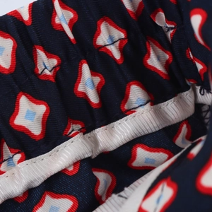 Detail view of elastic waistband and geometric print pattern on satin trousers