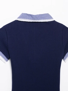 Dettaglio del top in maglia blu scuro con colletto a quadretti e pizzo bianco fine