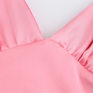 Détail du tissu en satin rose avec col en V profond et coutures froncées délicates