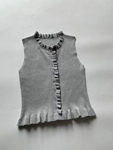 Flat lay detail of grey sleeveless knit cardigan with ruffled edges and round buttons