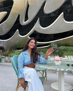 Blue and white striped cropped shirt and white trousers worn in an outdoor cafe setting