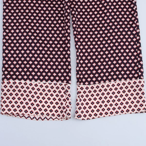 Detailed close-up of wide hem stitching and geometric diamond print on satin trousers