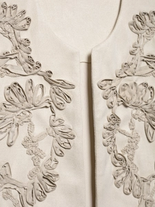 Macro shot of 3D ribbon floral embroidery on a vintage beige suede vest