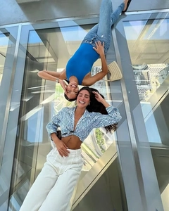 Creative overhead reflection of blue tie-front shirt and striped summer vacation outfit