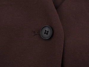 Close-up of black four-hole resin button and neat stitching on dark brown vest