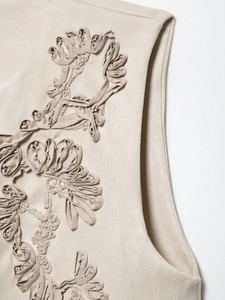 Close-up of 3D floral embroidery details on a cream-colored vintage knitted vest