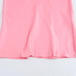 Vue détaillée de l'ourlet de la robe en satin rose montrant la texture lisse et la couture