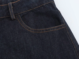 Gros plan du tissu denim bleu foncé avec coutures contrastées et détails de poche