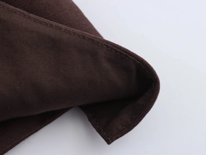 Macro view of dark brown canvas fabric showing detailed stitching and woven texture