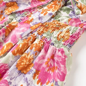 Détail du tissu à fleurs smocké montrant la texture élastique et les motifs colorés