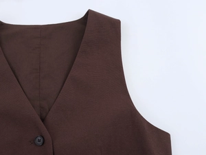 Detail of V-neck brown vest showing single black button and high-quality fabric texture