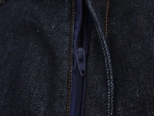 Vue macro du tissu denim avec fermeture éclair en métal et détails de couture orange