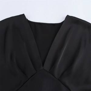 Détail d'une robe longue en satin noir élégante avec décolleté en V et détails plissés