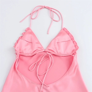 Détail d'un haut en satin rose avec bords à volants et fines bretelles licou à nouer