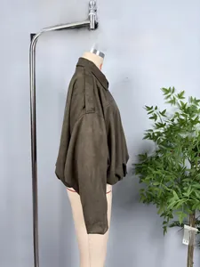 Close-up of olive green suede bomber jacket with shoulder epaulettes and gathered hemline