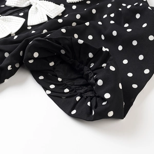 Detailaufnahme der elastischen Manschetten und weißen Schleifen am Polka-Dot-Kleid