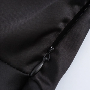 Gros plan sur la fermeture éclair invisible et la texture satinée d'une robe noire
