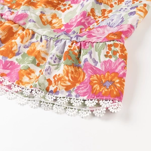 Détail de la robe fleurie avec broderie en dentelle blanche et motifs colorés élégants