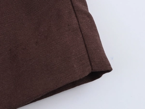 Close-up detail of dark brown pleated fabric texture and neat stitching on high-quality pants