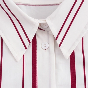 Detalle del cuello de camisa marfil con rayas granates y botón de resina blanca