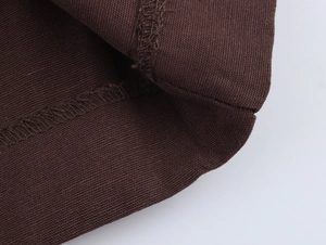 Close-up of the professional stitching and pleated texture on dark brown trousers